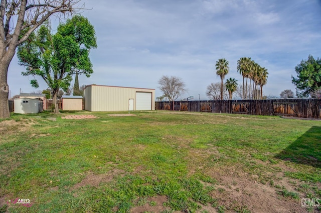 view of yard with a garage, an outbuilding, and fence