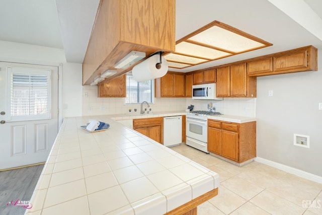 kitchen with tile countertops, white appliances, baseboards, brown cabinets, and tasteful backsplash