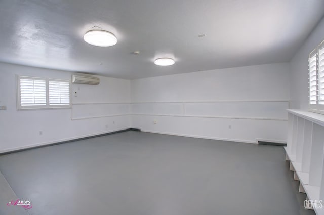 below grade area featuring a wall unit AC, plenty of natural light, and baseboards