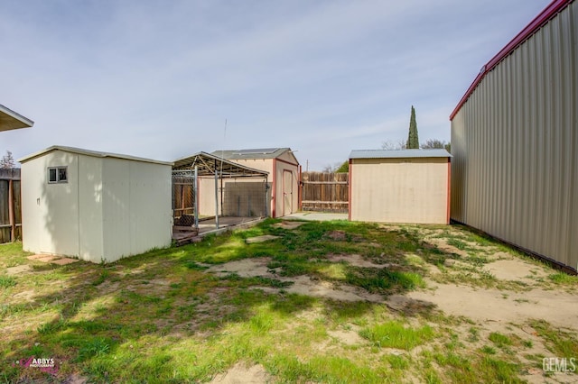 view of yard featuring a storage shed, an outdoor structure, and a fenced backyard