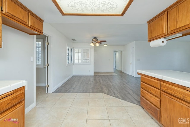 kitchen with brown cabinetry, tile countertops, and light tile patterned floors