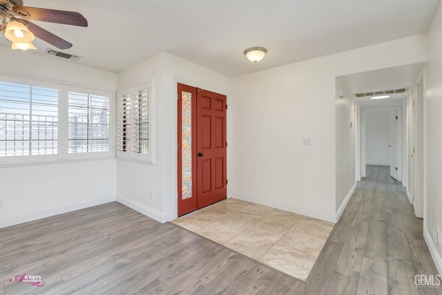 foyer featuring baseboards, visible vents, ceiling fan, and light wood finished floors