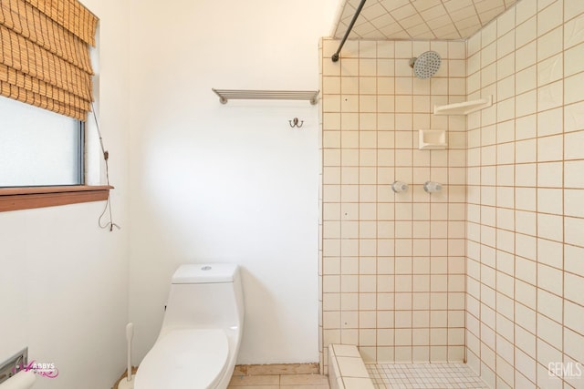 full bath featuring tiled shower, toilet, and tile patterned floors