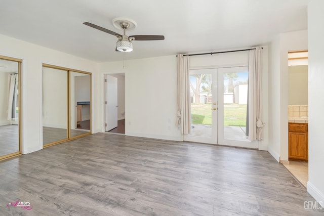 unfurnished bedroom featuring ensuite bath, access to exterior, french doors, light wood-type flooring, and two closets