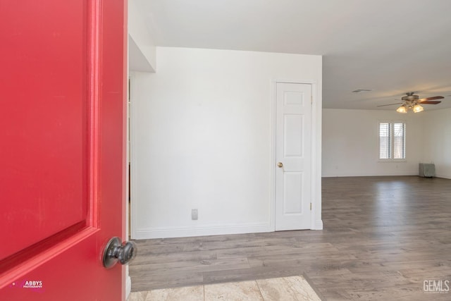 empty room featuring ceiling fan, wood finished floors, and baseboards