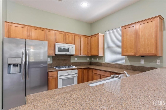 kitchen featuring appliances with stainless steel finishes, light stone countertops, and sink