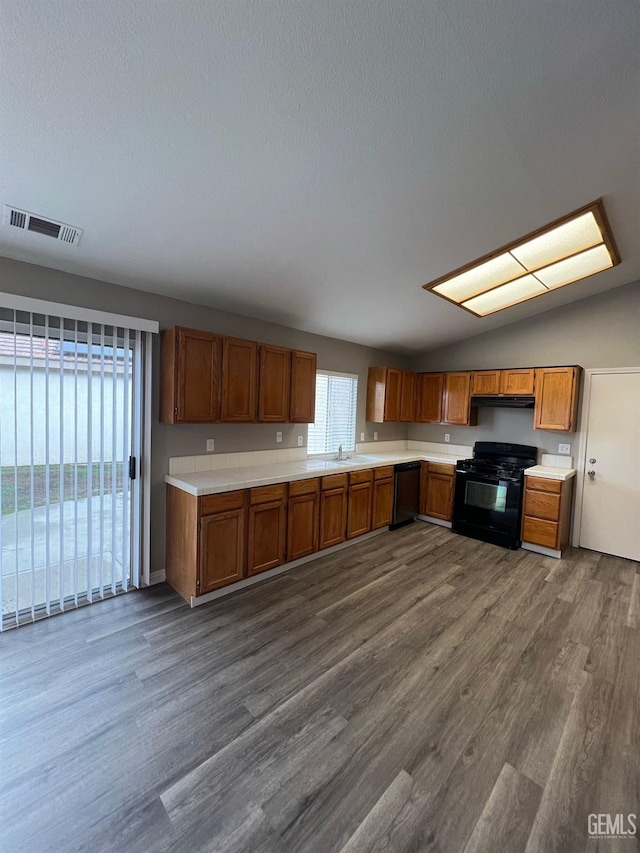 kitchen featuring dark hardwood / wood-style floors, dishwasher, lofted ceiling, sink, and black gas stove