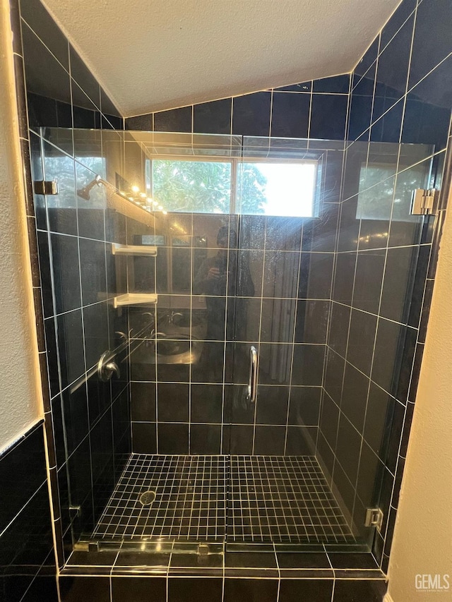 bathroom with a shower with door and lofted ceiling