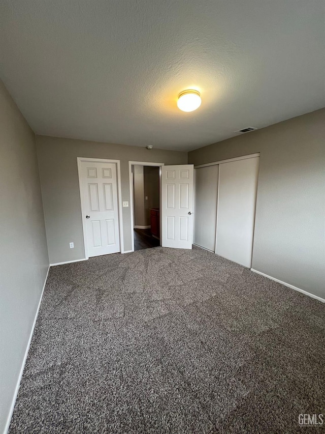 unfurnished bedroom featuring a textured ceiling and dark carpet