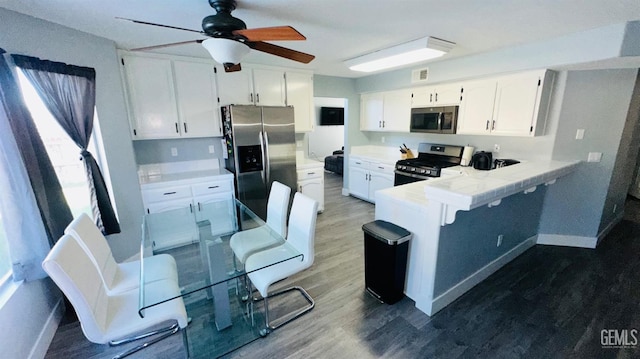 kitchen with hardwood / wood-style floors, white cabinetry, kitchen peninsula, and appliances with stainless steel finishes