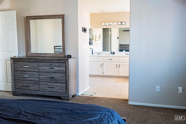 bedroom featuring light tile patterned floors, ensuite bath, and sink