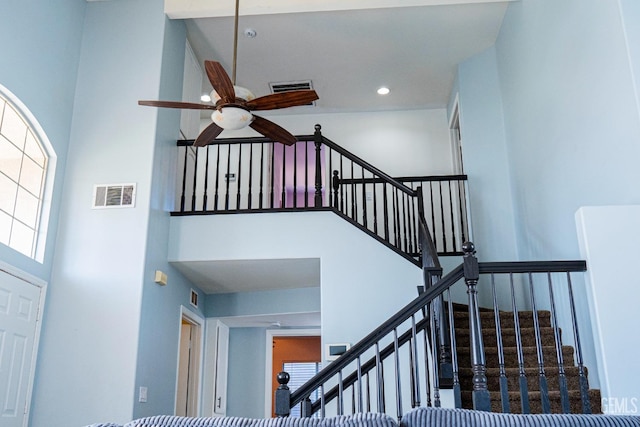 stairway featuring a high ceiling and ceiling fan