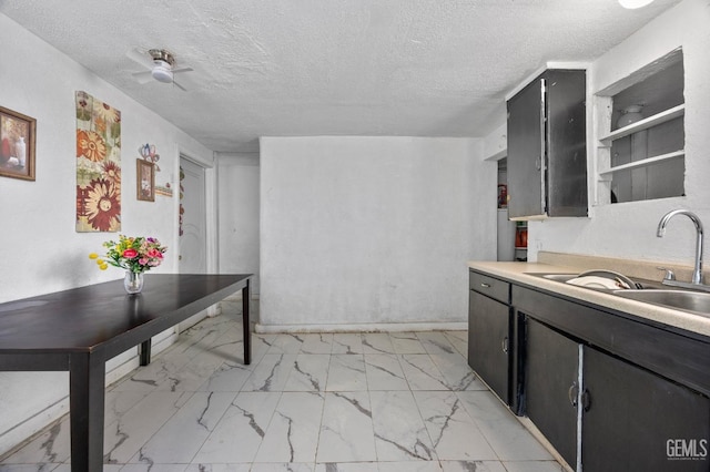 kitchen featuring light countertops, marble finish floor, a sink, and a textured ceiling
