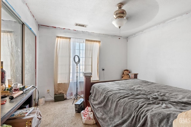 carpeted bedroom featuring a textured ceiling, a closet, and ceiling fan