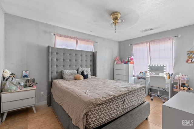 bedroom with ceiling fan, light tile patterned floors, and a textured ceiling