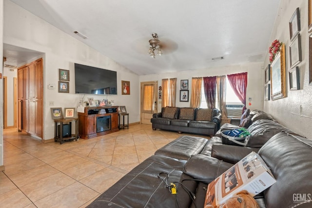 living room featuring ceiling fan, light tile patterned floors, and vaulted ceiling