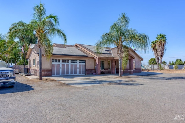 ranch-style home featuring solar panels and a garage