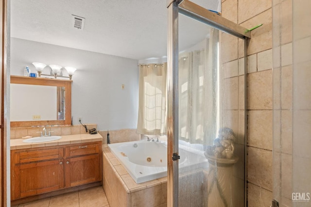 bathroom with tile patterned flooring, a textured ceiling, vanity, and separate shower and tub