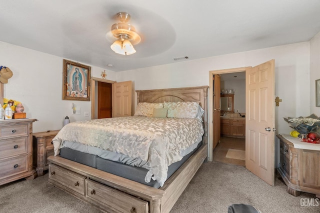 bedroom featuring connected bathroom, ceiling fan, and light carpet