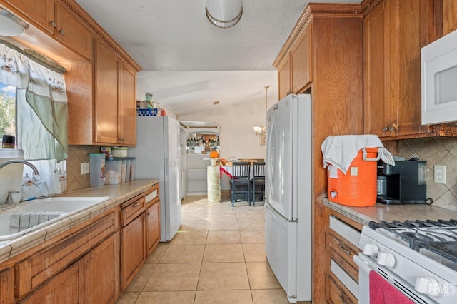 kitchen featuring tile countertops, white appliances, lofted ceiling, sink, and decorative backsplash