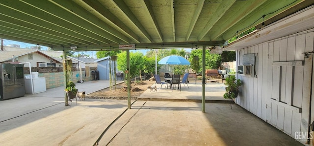 view of patio / terrace with a fenced backyard, outdoor dining space, a shed, washer / dryer, and an outdoor structure
