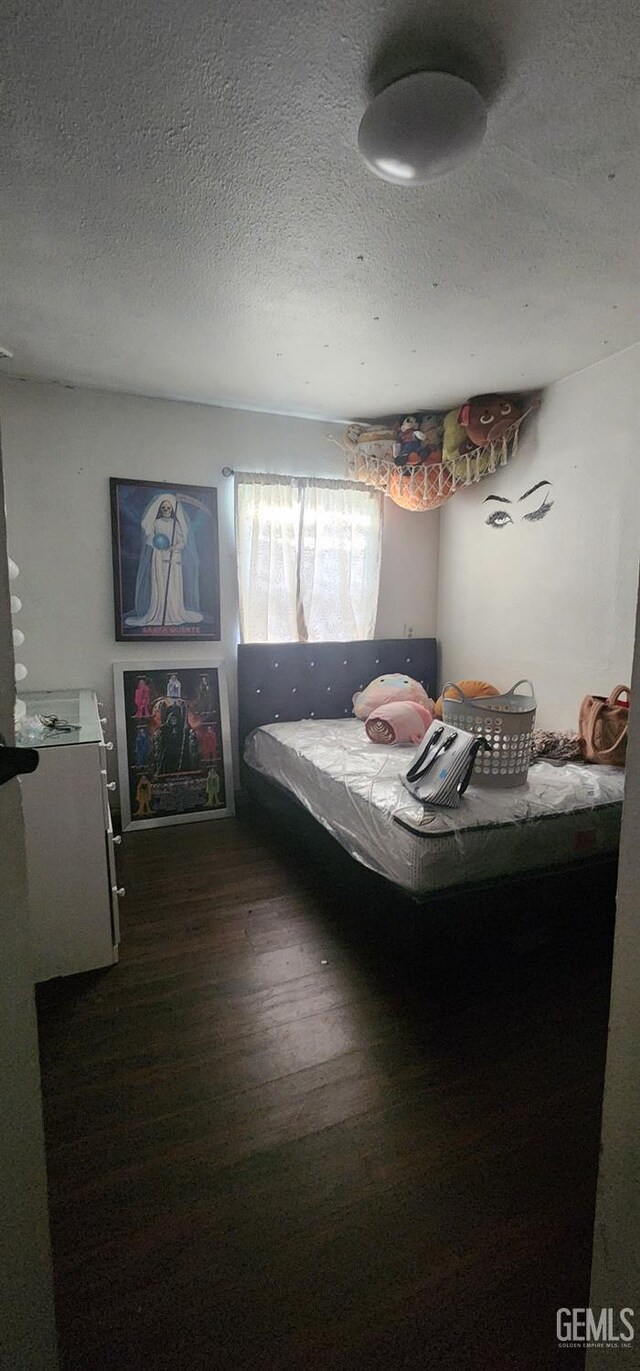 bedroom featuring a textured ceiling and dark wood-style flooring