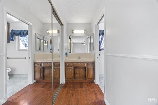 bathroom with hardwood / wood-style floors, vanity, a textured ceiling, and ceiling fan