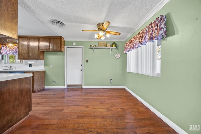 kitchen featuring a textured ceiling, ceiling fan, crown molding, and dark wood-type flooring