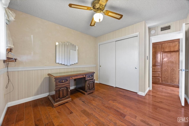 home office with a textured ceiling, ceiling fan, and dark wood-type flooring