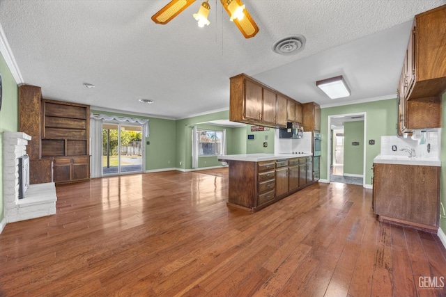 kitchen featuring ceiling fan, dark wood-type flooring, kitchen peninsula, crown molding, and decorative backsplash