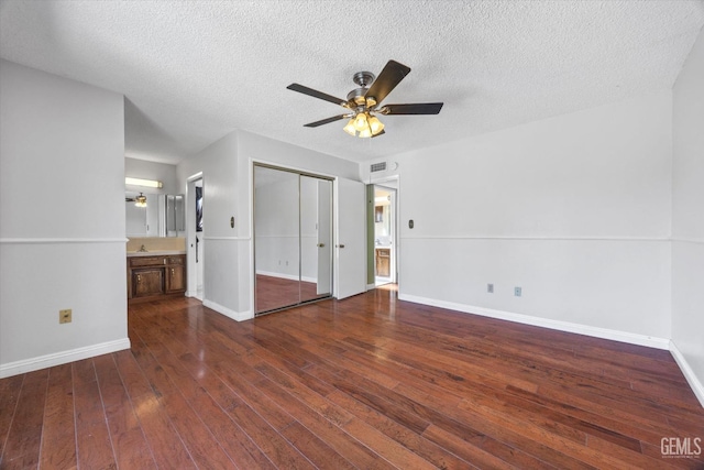 unfurnished bedroom featuring connected bathroom, ceiling fan, dark hardwood / wood-style flooring, and a textured ceiling