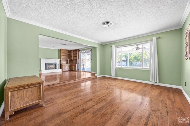 unfurnished living room with hardwood / wood-style floors, ornamental molding, and a textured ceiling