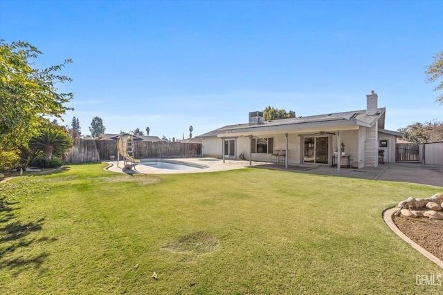 rear view of property featuring a lawn, ceiling fan, a fenced in pool, and a patio