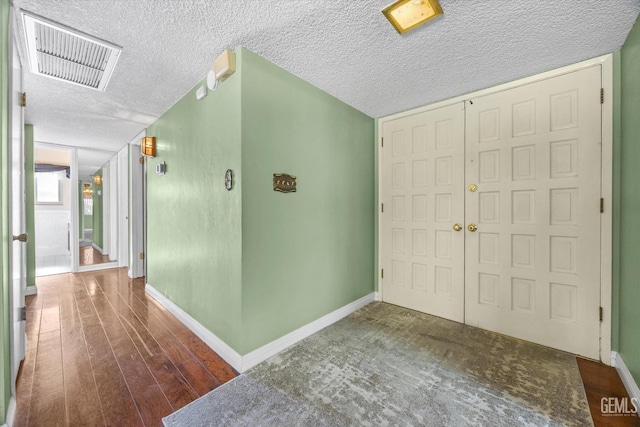 entrance foyer with a textured ceiling and dark hardwood / wood-style floors