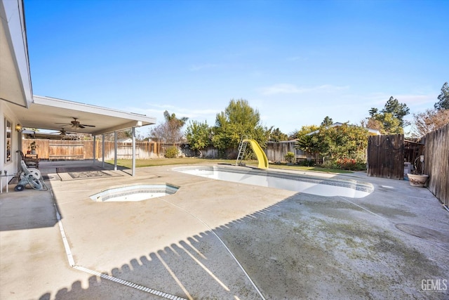 view of pool featuring ceiling fan, an in ground hot tub, a patio, and a water slide