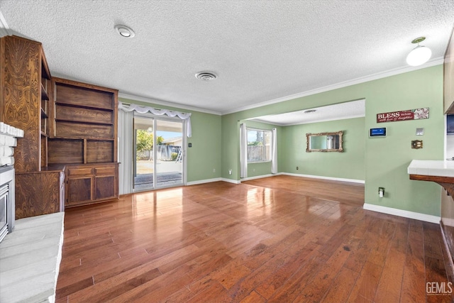 unfurnished living room with a textured ceiling, hardwood / wood-style flooring, and ornamental molding