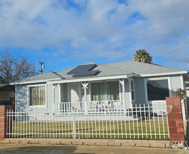 ranch-style house featuring solar panels, covered porch, and a front lawn