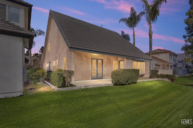 back house at dusk with a yard and a patio area