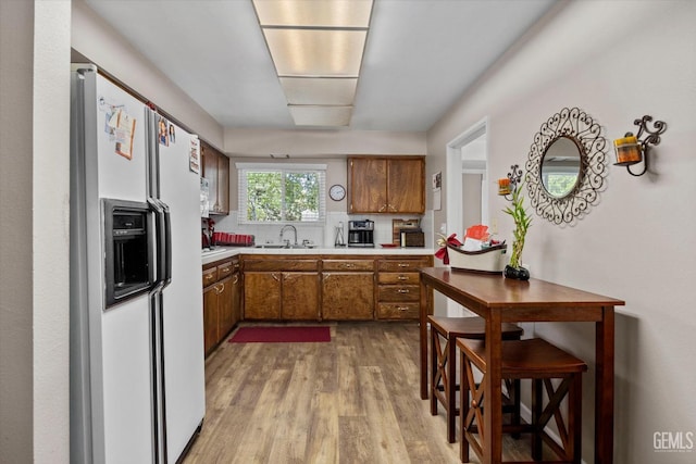 808 La Puente Dr, Bakersfield, CA 93309 - kitchen with white refrigerator with ice dispenser, brown cabinets, a sink, light wood-style floors, and light countertops