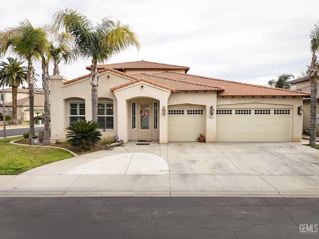 mediterranean / spanish home featuring a garage, driveway, a tiled roof, and stucco siding