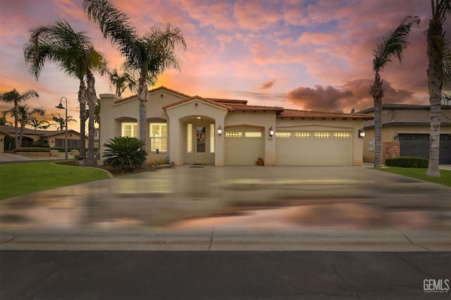 mediterranean / spanish-style house with a garage, concrete driveway, and stucco siding