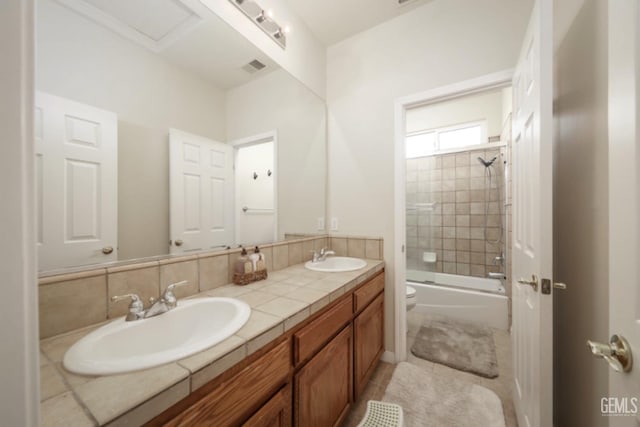 bathroom with toilet, double vanity, bath / shower combo with glass door, and a sink