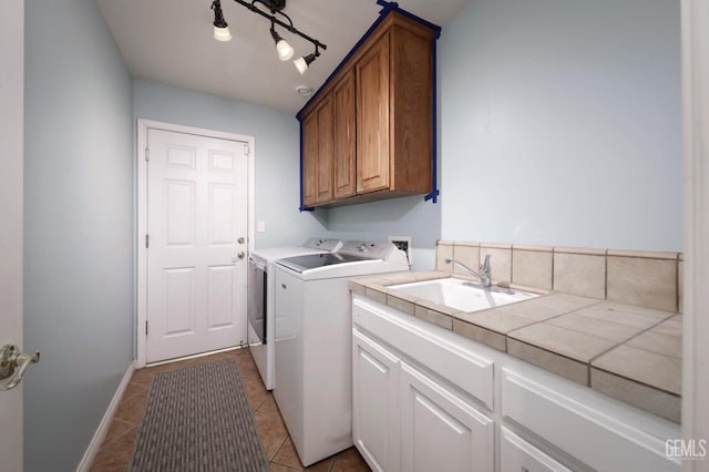 laundry area with light tile patterned floors, a sink, baseboards, independent washer and dryer, and cabinet space