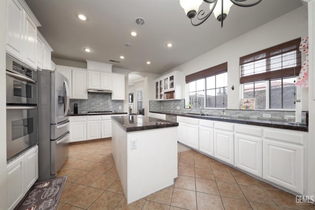 kitchen with appliances with stainless steel finishes, a center island, light tile patterned flooring, and white cabinetry