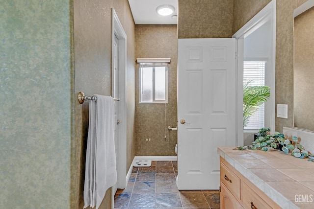 full bath with baseboards and stone tile flooring