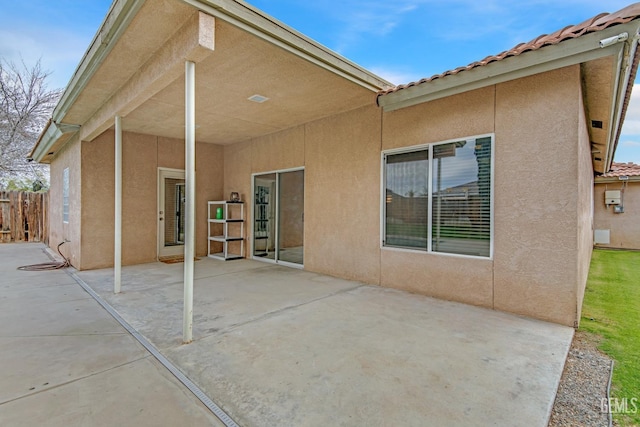 back of house featuring a tiled roof, a patio area, fence, and stucco siding