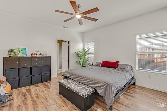 bedroom featuring baseboards, a ceiling fan, visible vents, and light wood-style floors