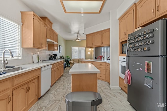 kitchen with marble finish floor, stainless steel appliances, light countertops, a kitchen island, and a sink