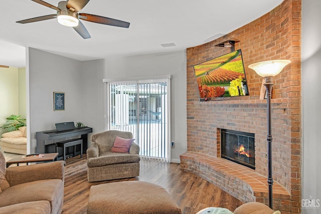 living room with ceiling fan, a fireplace, and wood finished floors