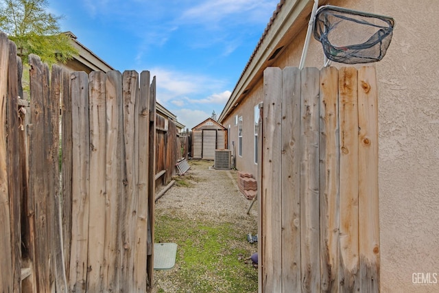 view of yard featuring an outdoor structure, fence, a storage shed, and central AC unit